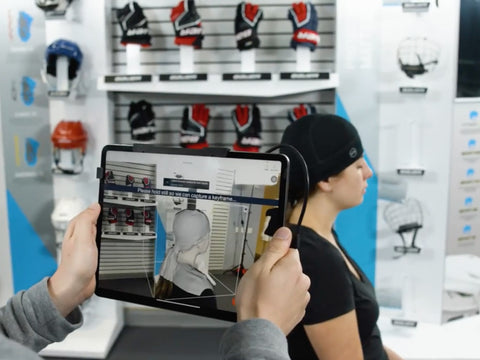 woman sitting while hockey retail employee takes her head scan with iPad