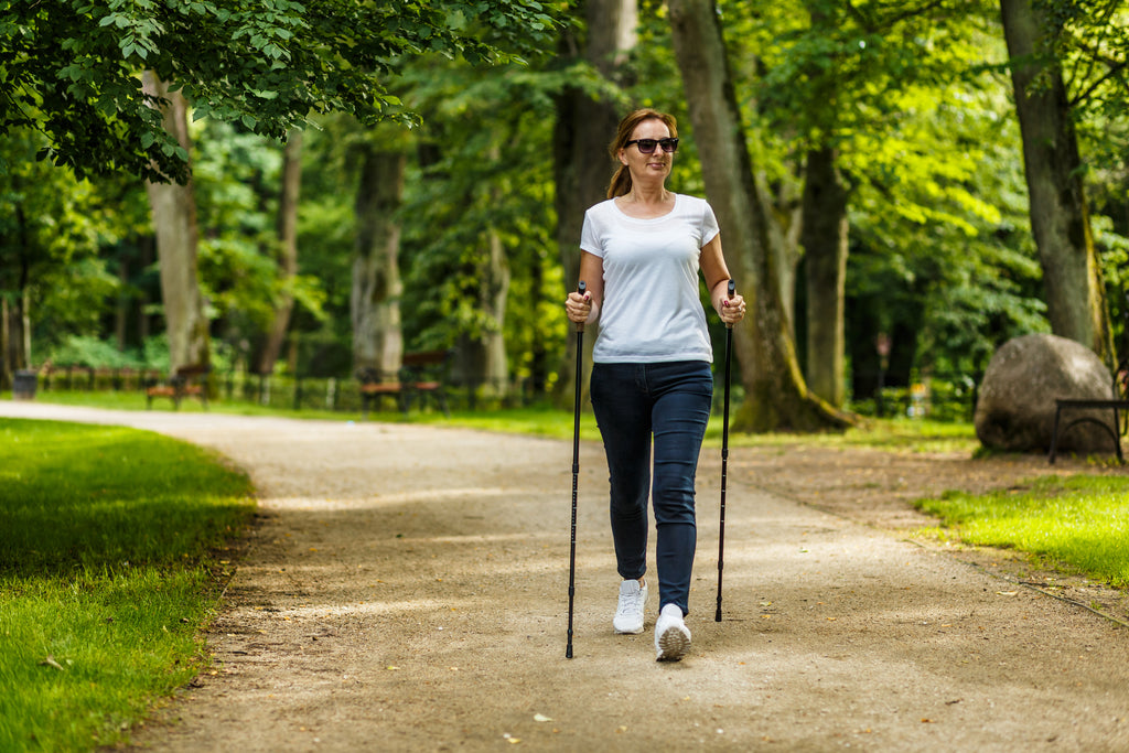 Frau trainiert Nordic Walking im Park