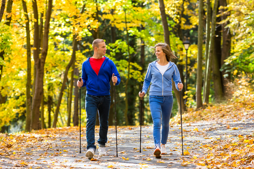 Mann und Frau trainieren Nordic Walking im Wald