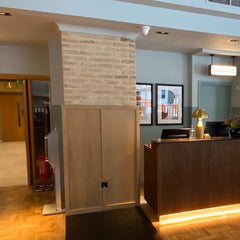 A cream brick slip pillars is next to a reception desk, with a cupboard at it's base.