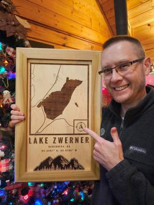 Greg holding a custom made map of Lake Zwerner in front of a Christmas tree
