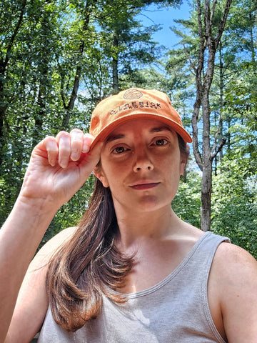 April wearing an orange G. Loebick Woodworks hat. When you buy a custom wood map, get a free hat