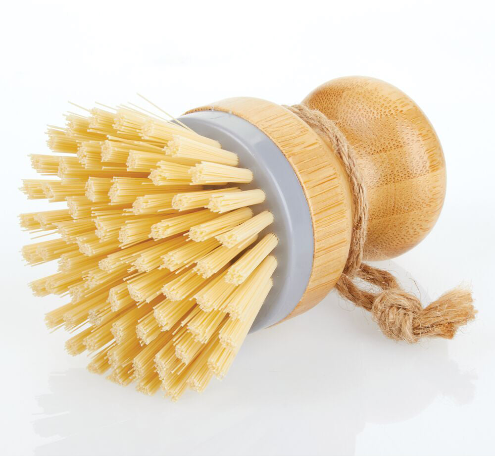 Kitchen Scrub Brush with Bamboo Handle and Natural Bristles Laying on It's Side with a Slight Reflection Underneath