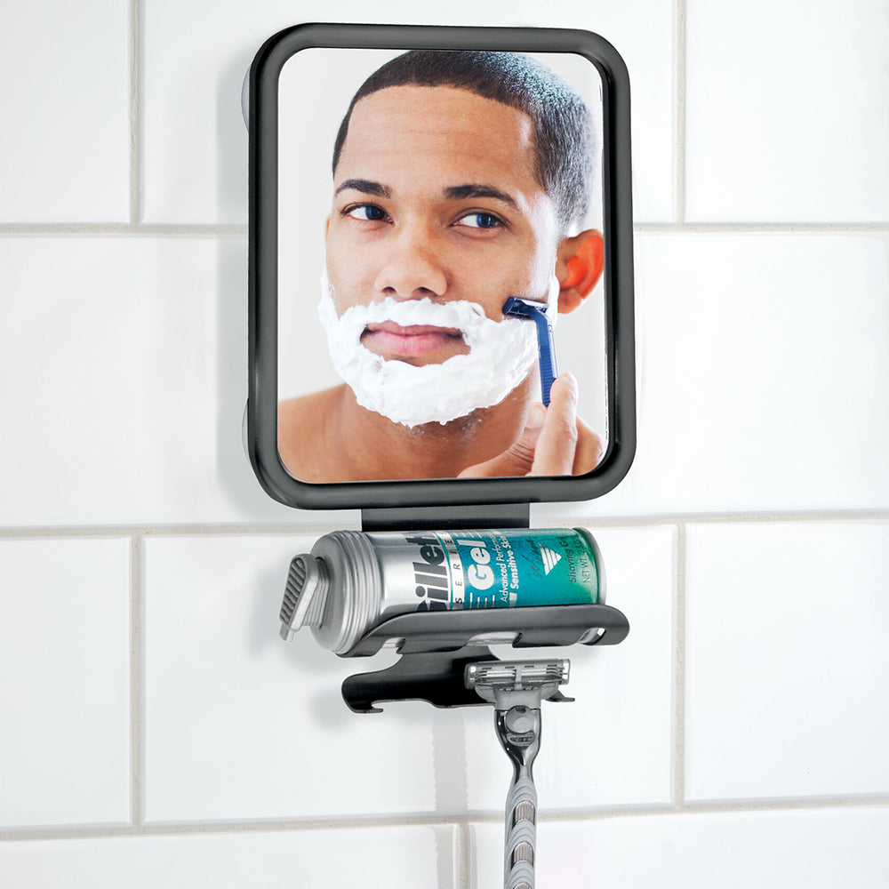 Small Black Suction Mirror on White Tile Wall with Shaving Cream and Razor Storage Hooks Showing Reflection of Young Male Shaving His Face