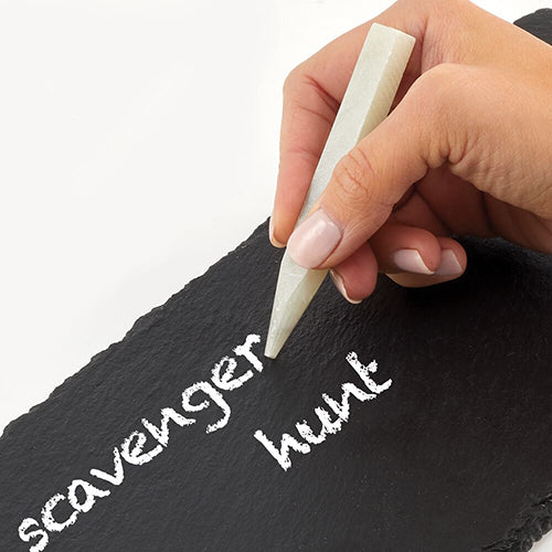 Hand Holding Chalk Writing Scavenger Hunt onto a Slate Tray on White Background