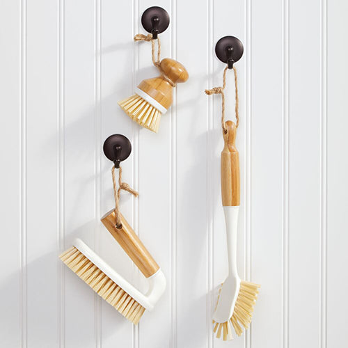 Three Cleaning Scrub Brushed Hanging on Hooks Against White Wainscoting Wall