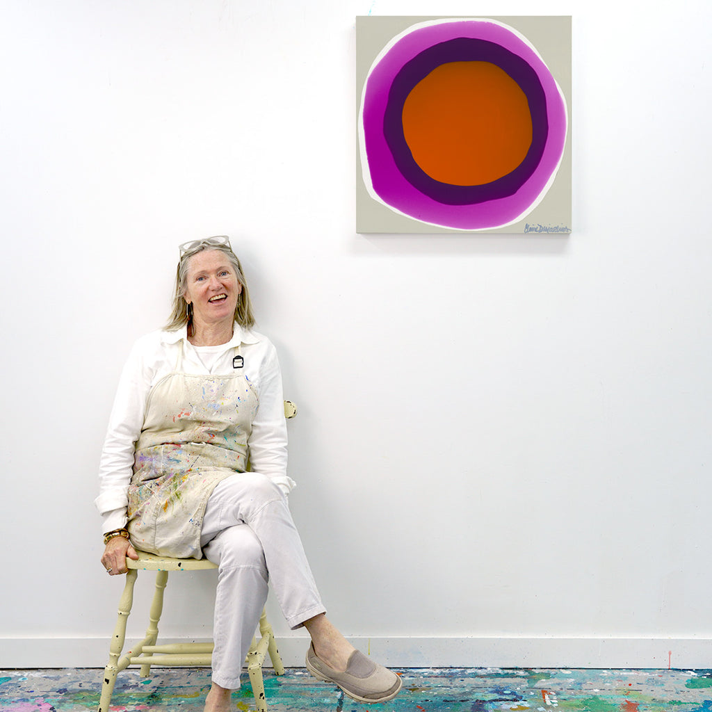 Artist/painter, Claire Desjardins, sits in front of her red, purple and taupe abstract painting, "Right On!".