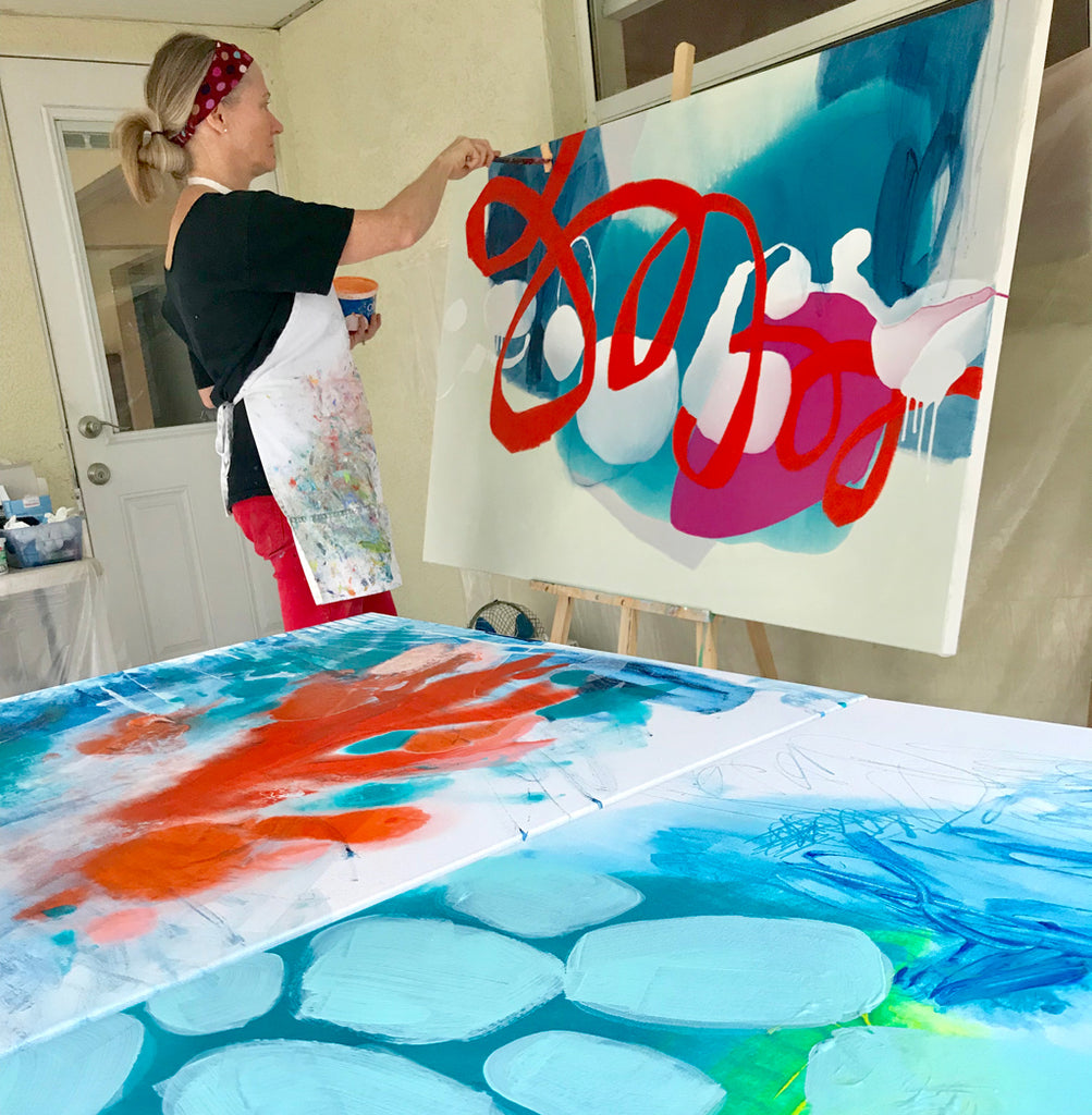 Artist Claire Desjardins, painting a colourful abstract painting in her art studio.