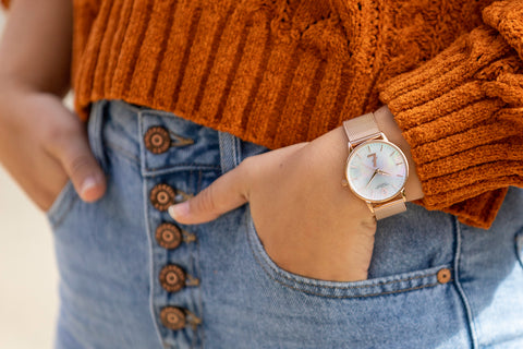 A woman stylishly wearing the Coin Vigilante Women's Rose Gold Bitcoin Watch with jeans and a sweater