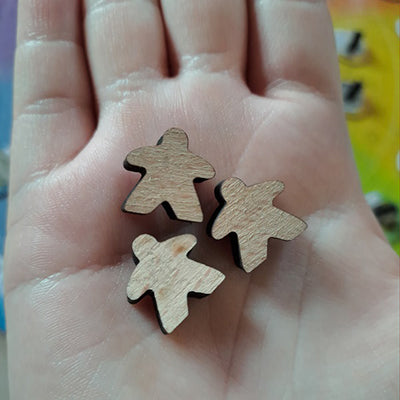 A hand holding three meeple