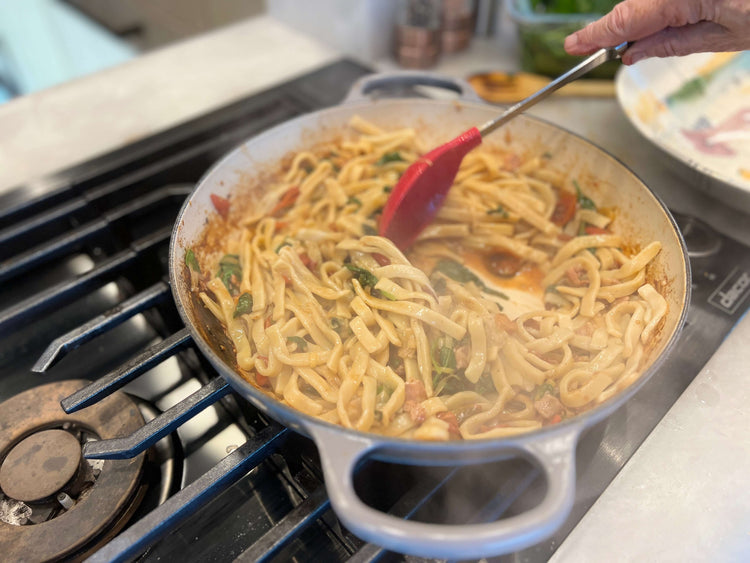 Image of Transfer cooked pasta from cooking pot to skillet with tongs...