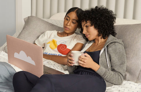 Couple laying in bed looking at a laptop together