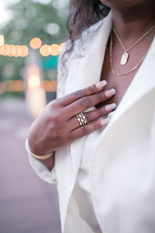 woman with a yellow gold pendant necklace and paper clip chain necklace from Bremer Jewelry