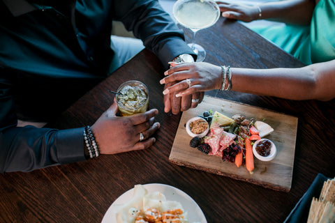 a couple with a Rolex watch, wedding bands, bead bracelets and white diamond bracelet