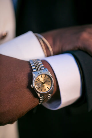 a man with a gold face Rolex watch on