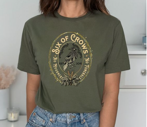 model wearing a forest green t-shirt with a oval frame deisng of a crow printed on it