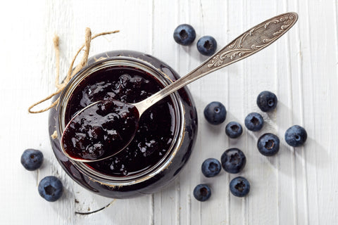 Blueberry Jam with whole blueberries around the jar