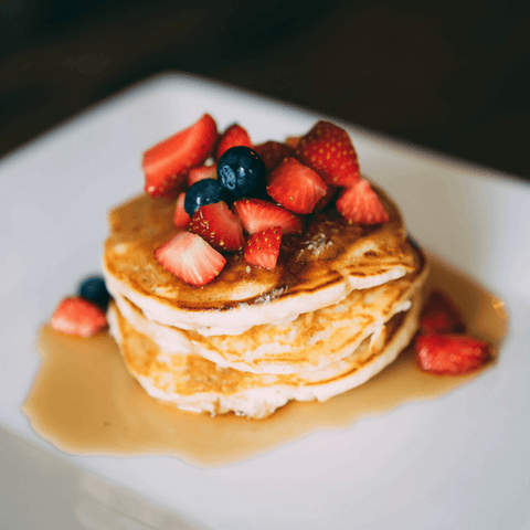 Stack of pancakes with syrup, strawberries and blueberries