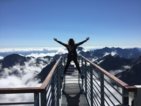 a girl looking happy staring at the mountains and the clouds 