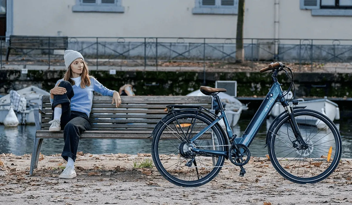 Donna seduta nel parco che guarda la sua bici elettrica Fiido C11pro