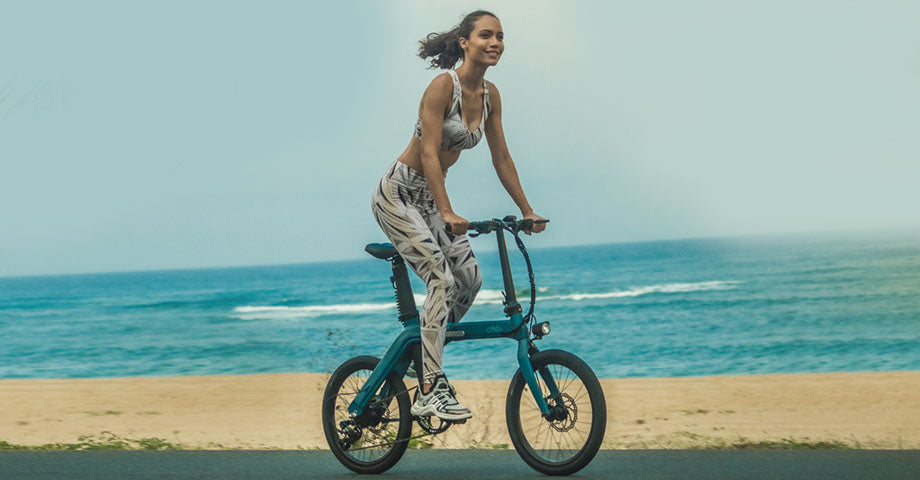 Donna che guida una bicicletta elettrica in riva al mare