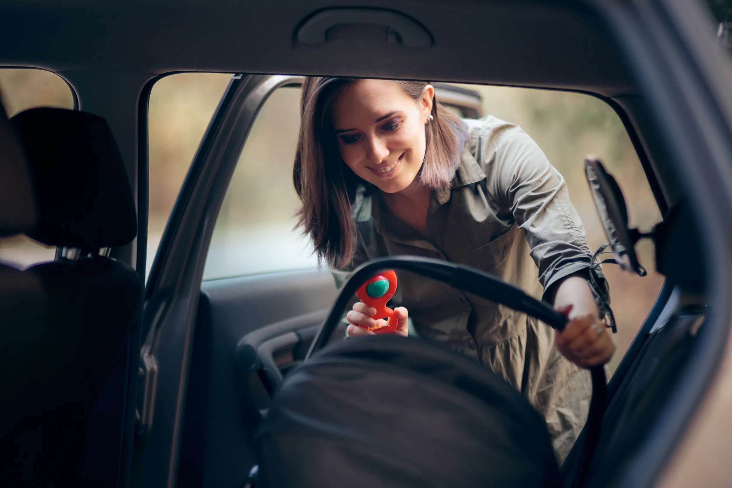 Young mother putting car seat in the back seat of her car