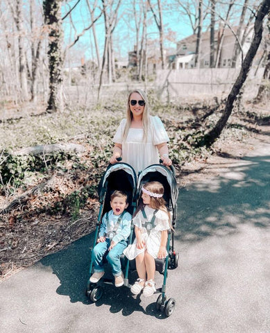 Woman pushing two children in her double open box stroller at a park