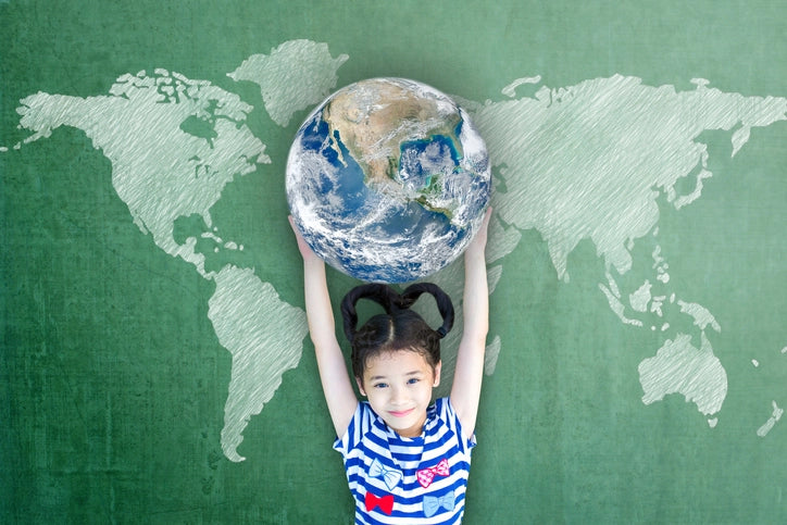 Girl holding a globe in front of a chalkboard map of the world