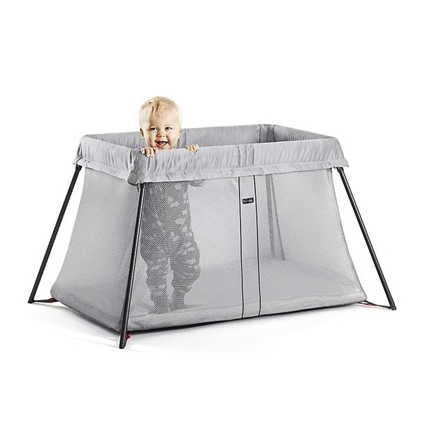 Happy baby standing in gray BabyBjörn Travel best crib 2024