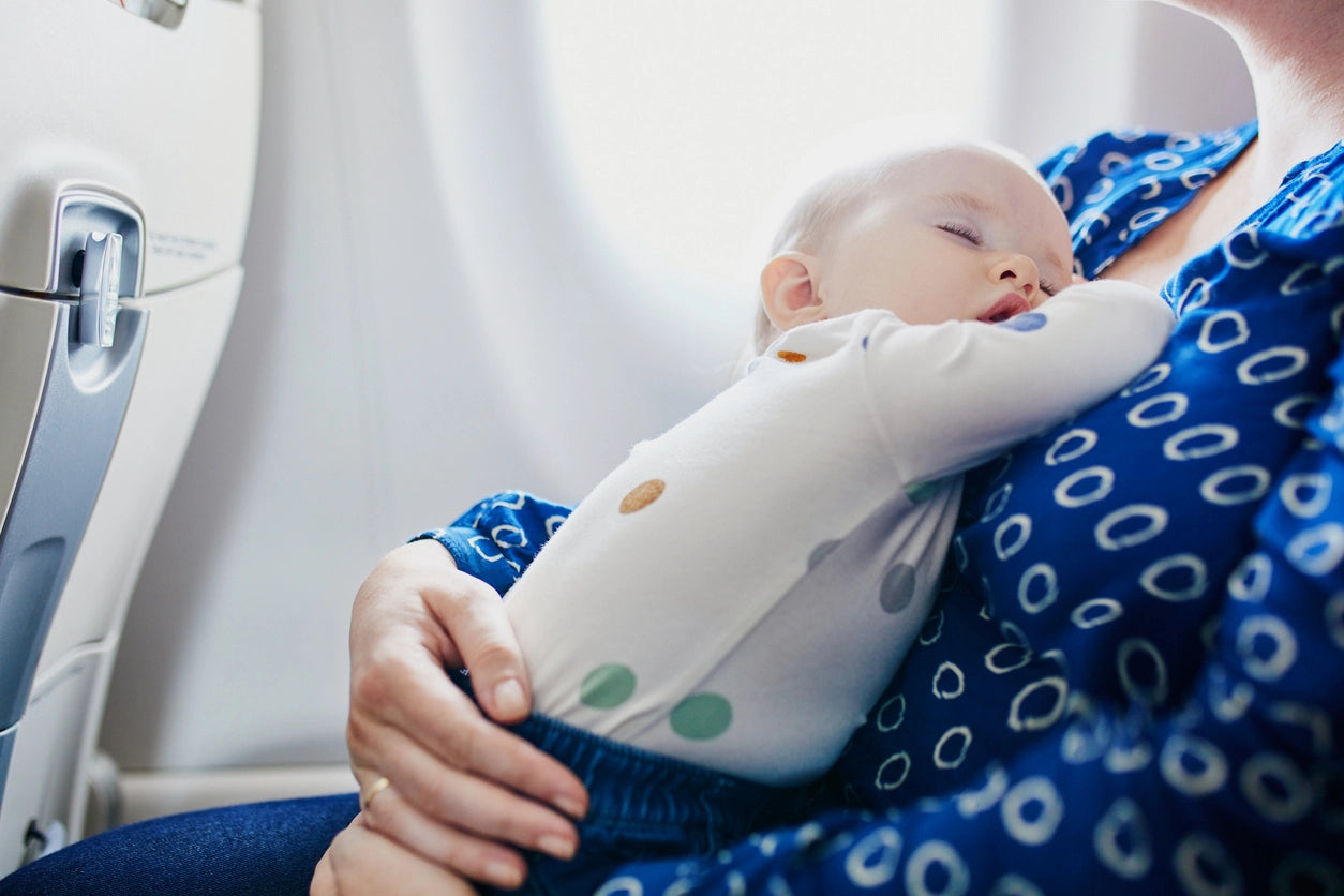 Baby boy sleeping on his mom while seated on a plane