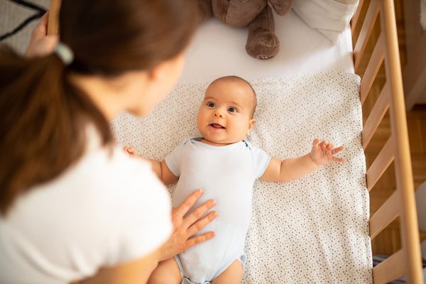 Mother putting a baby in a best crib 2024