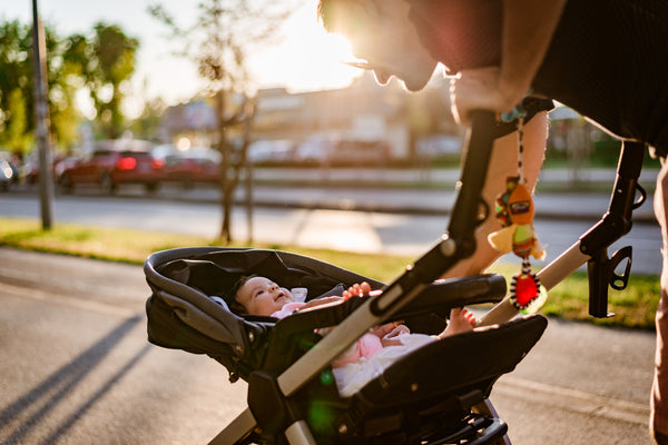 A dad pushing a baby in a stroller with stroller accessories