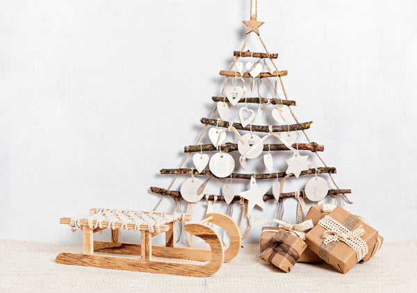 DIY Christmas tree made with sticks and wooden cutouts and baby items on sale wrapped in craft paper