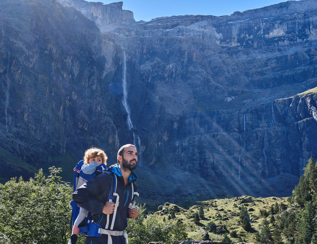 Father with young daughter in a baby carrier backpack hiking in the mountains