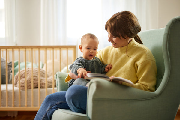 Mother reading a book to her baby in a rocking chair