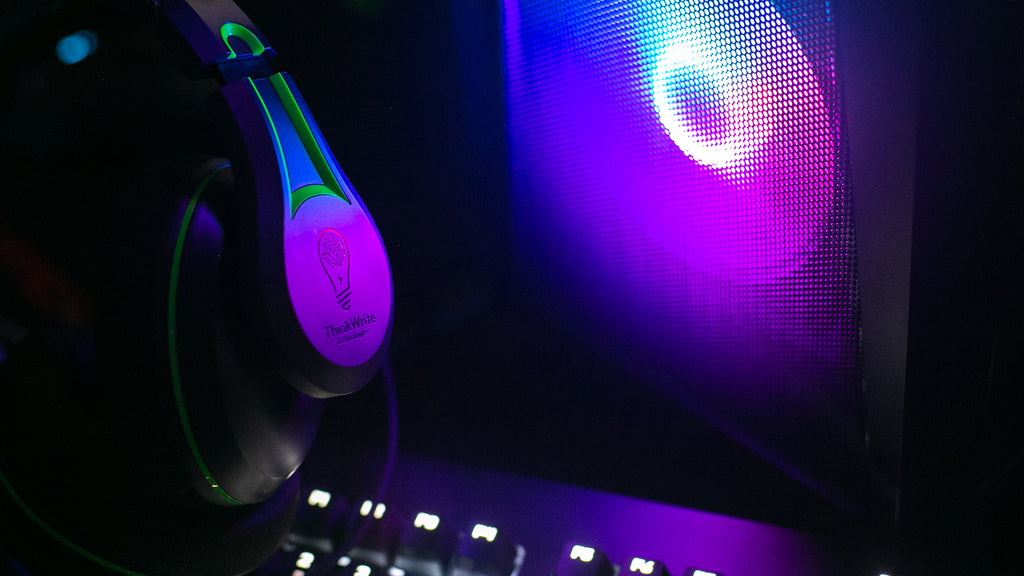 Image of a student wearing the TWT Audio 250XG Victory Gaming Headset in a dark setting, positioned in front of a gaming PC illuminated with neon-colored lights.