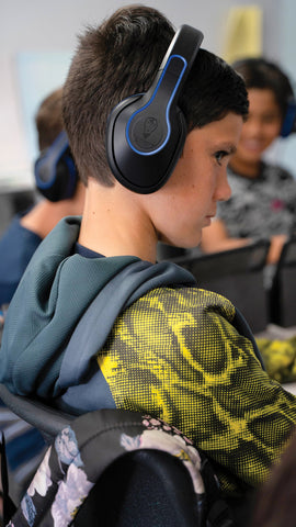 Student in a classroom setting wearing Revo wireless headphones by TWT Audio.