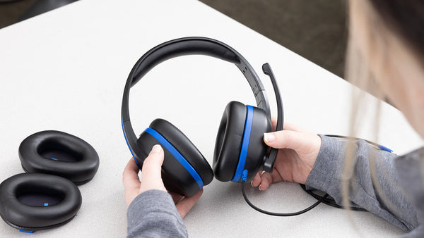 Student adjusting TWT Audio's Revo headphones featuring easy-to-remove and replace modular ear cushions on a desk