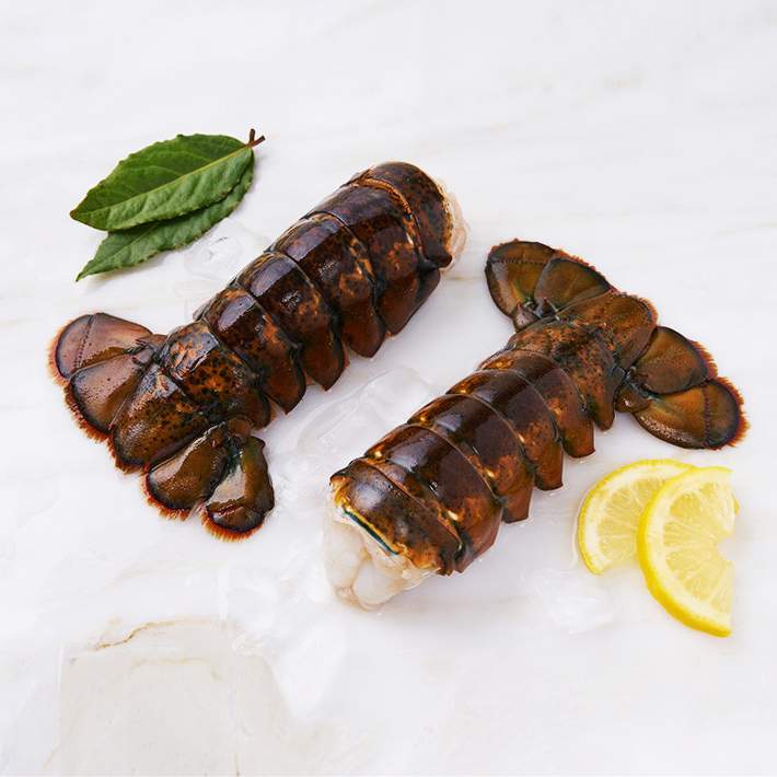 Lobster Tails on marble with lemon and herbs