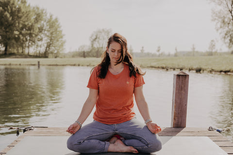 Manon van Flowee op een meditatiekussen bij het water