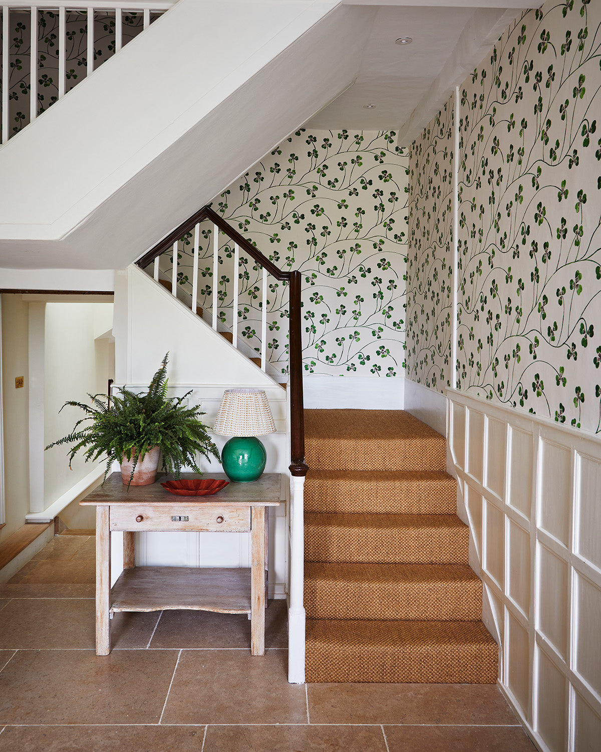 hallway with green clover wallpaper, wood floor and rattan stair carpet