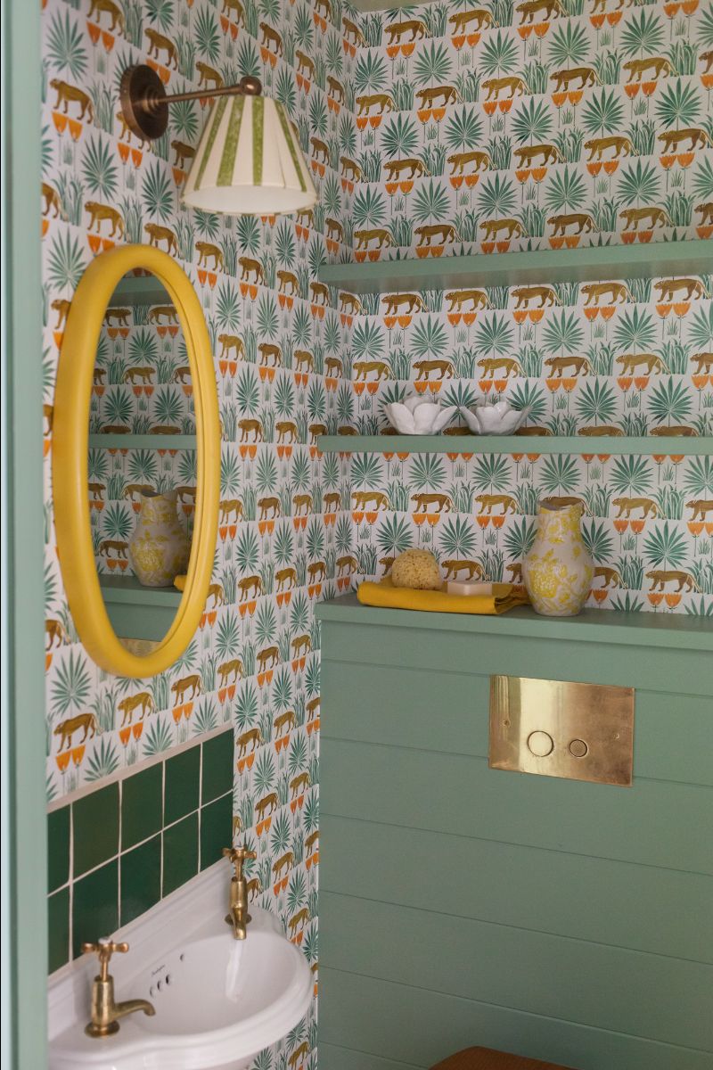 Green and gold bathroom with ceramic sink, yellow mirror and tropical Lioness & Palms wallpaper
