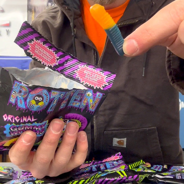 A person opening a pack of 'Rotten' gummies with colorful packaging.