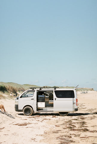 Van parked on a beach set up for camping  