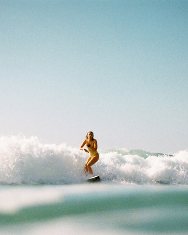 Girl standing up in white wash surfing towards the shore