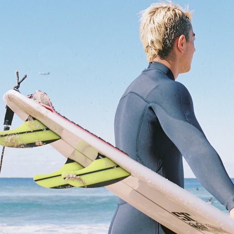 Guy in wetsuit holder board up after a surf
