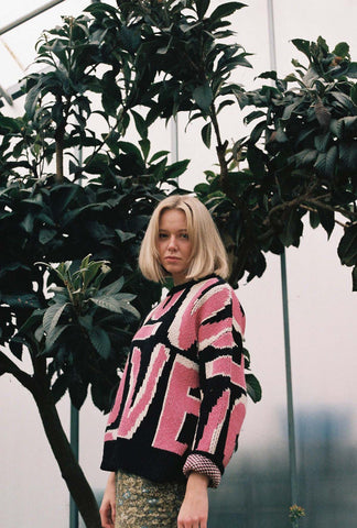 girl under a tree wearing an oversized knitted jumper