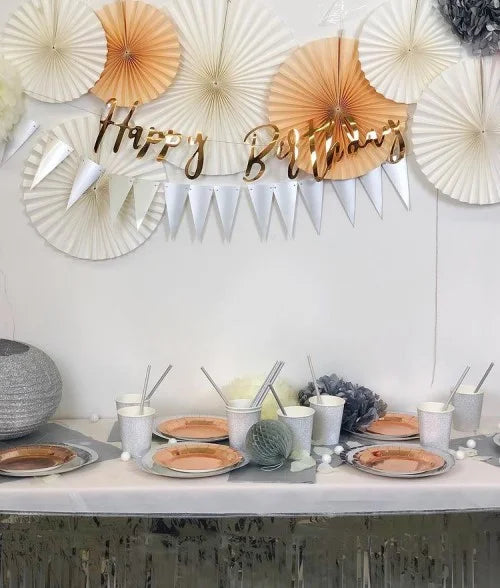 Geburtstagsdekoration in Silber, Apricot und Weiß mit 'Happy Birthday' Girlande, Fächern, Lampions, Wabenbällen und Partygeschirr