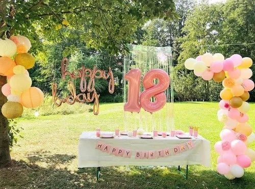 Geburtstagsdeko im Garten mit Lampion und Wabenballgirlande, Ballongirlande, 'Happy B-Day' Ballonschriftzug, '18' XXL Zahlenballon, 'Happy Birthday' Girlande und Tischdekoration in den Farben Rosa, Gelb, Apricot und Weiß