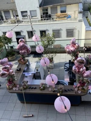 Blick von Oben auf Dekorierte Bar mit Lichterkette an der Lampions in Rosa hängen und rosa und roségoldenen Herz und Rund Heliumballons